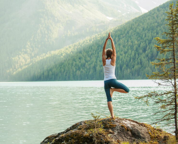 Young woman is practicing yoga at mountain lake